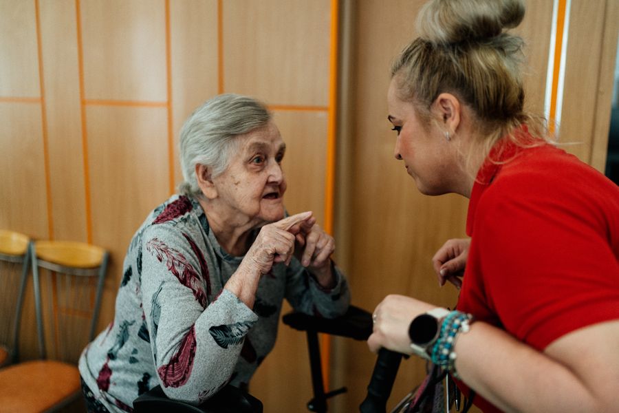 A caregiver listens to an older woman during a conversation.