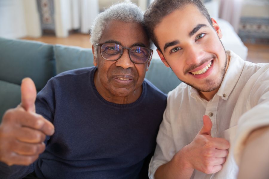 An older Black man and a younger man smiling together.